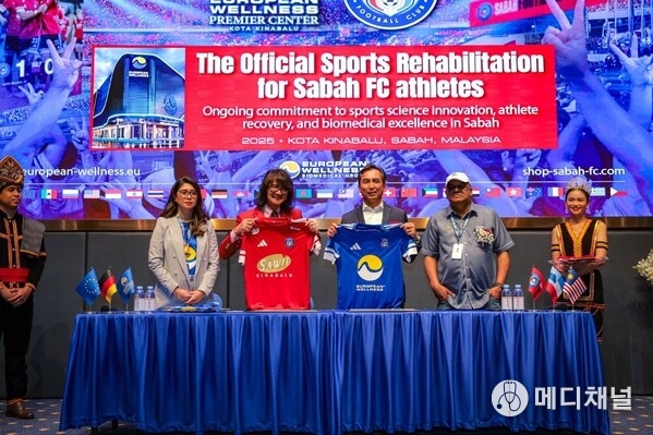 Officials from European Wellness and Sabah FC: (Pictured, from left) Dr. Natassia Sarah, Prof. Mike Chan, Tuan Md Joh Haji Wid, and Tuan Shamsuddin Bin Mohd Shah — exchange club jerseys in a symbolic gesture marking their newly formalized partnership for athlete rehabilitation and sports-science collaboration.