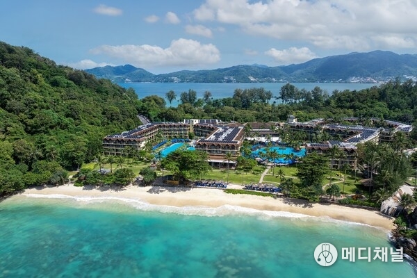 Aerial view of Phuket Marriott Resort & Spa, Merlin Beach, showcasing its expansive beachfront property with lush greenery, multiple swimming pools, and solar panel-equipped buildings along the turquoise coastline